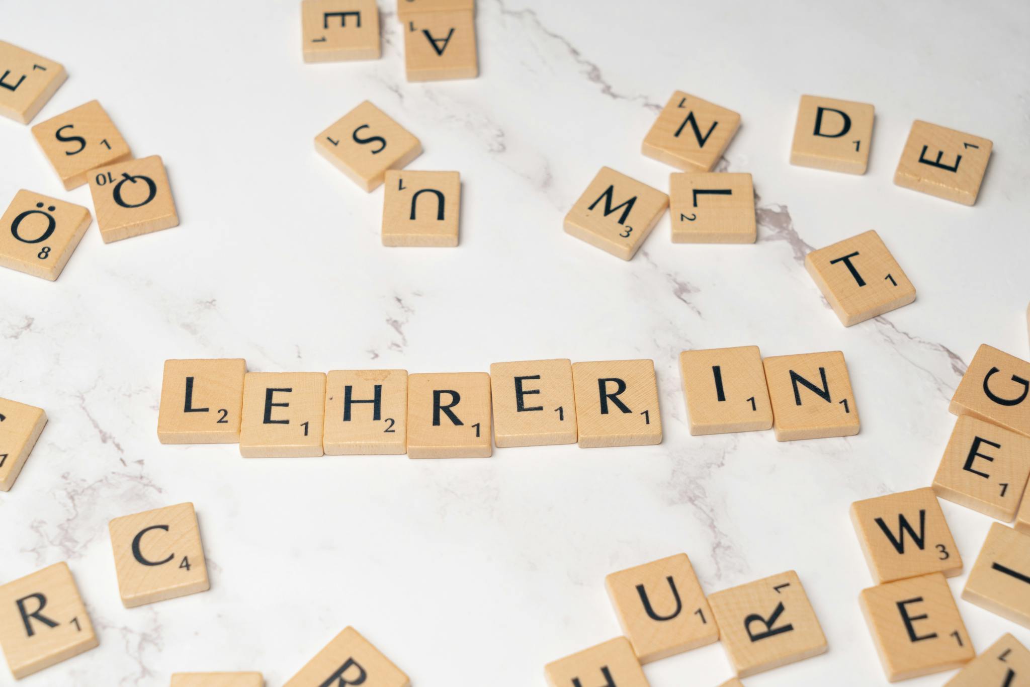 Scrabble tiles spelling 'Lehrerin', symbolizing education and language on a marble background.